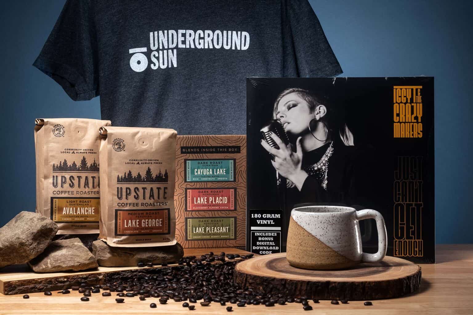 Bags of coffee, a vinyl record, and a t-shirt with the Underground Sun logo.